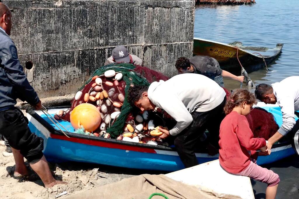 يقوم صيادو غزة بسحب قاربهم إلى الشاطئ.